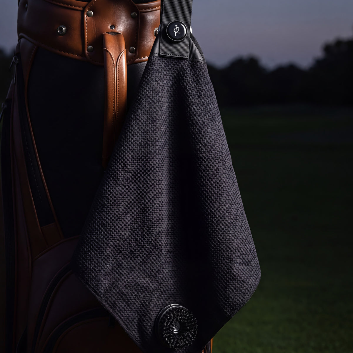 Ryft Golf Towel attached to a leather golf bag at dusk